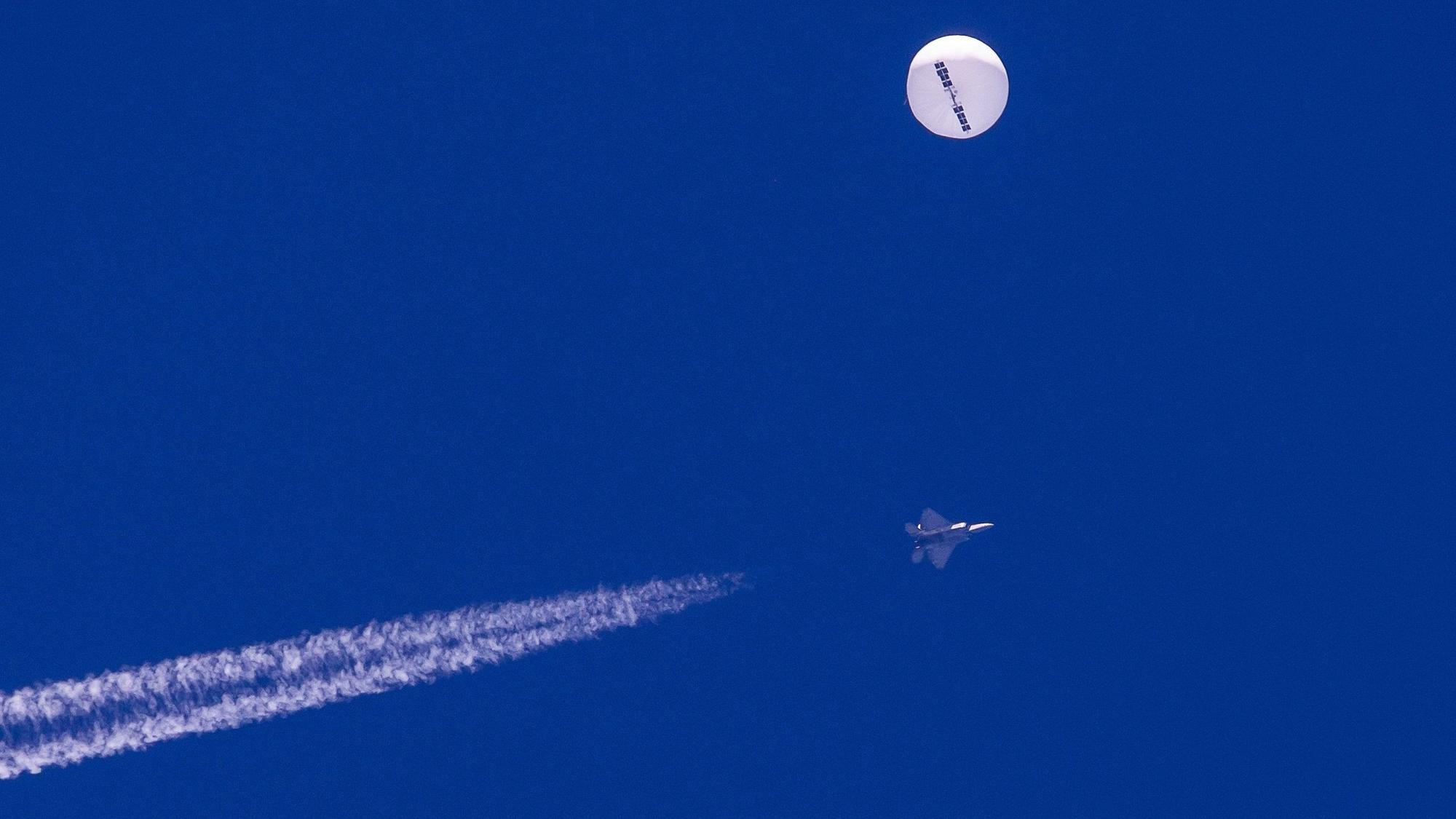 Ein großer Ballon schwebt über dem Atlantischen Ozean vor der Küste von South Carolina. Darunter sind ein Kampfjet und seine Kondensstreifen zu sehen.