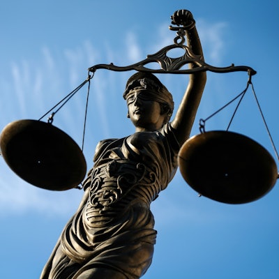 Eine Statue der Justitia hält eine Waage in der Hand.