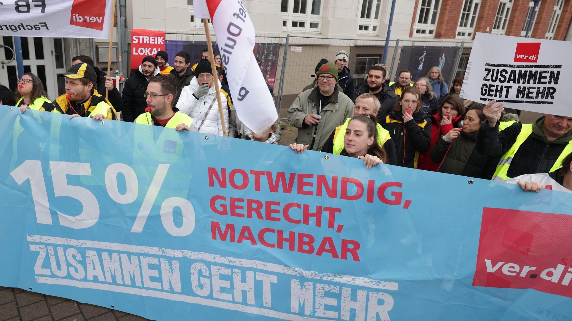 Vor einem Streiklokal demonstrieren Streikende der Post und DHL, dabei halten sie ein Banner mit der Aufschrift „15 % notwendig, gerecht, machbar, zusammen geht mehr.“