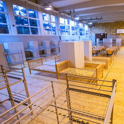 Eine Turnhalle ist mit Bettgestellen ausgestattet.