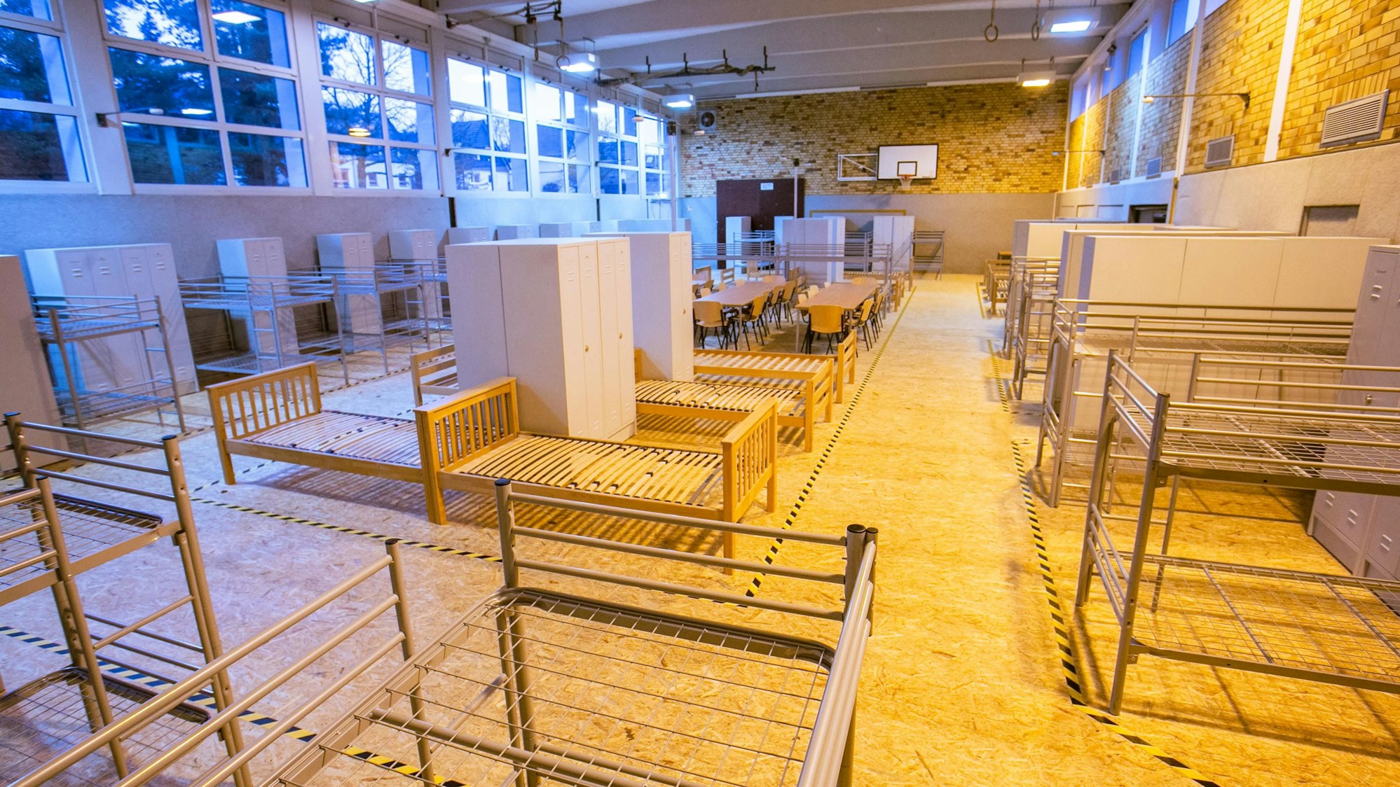 Eine Turnhalle ist mit Bettgestellen ausgestattet.