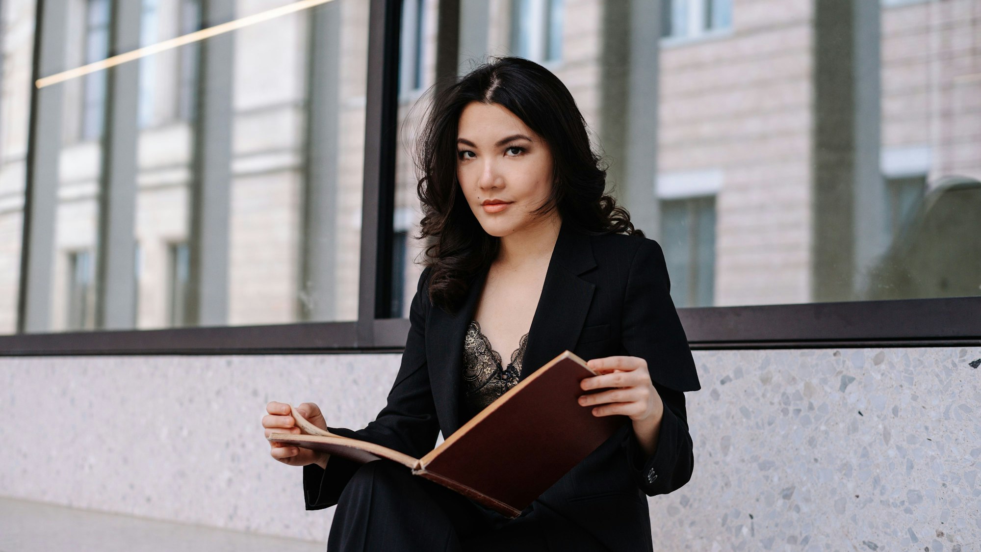 Melodie Zhao hat eine Parittur aufgeschlagen und schaut in die Kamera. Sie hat schwarze Haare und trägt schwarze Kleidung.