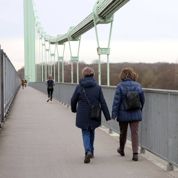 Zwei Frauen laufen über eine Brücke.