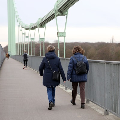Zwei Frauen laufen über eine Brücke.