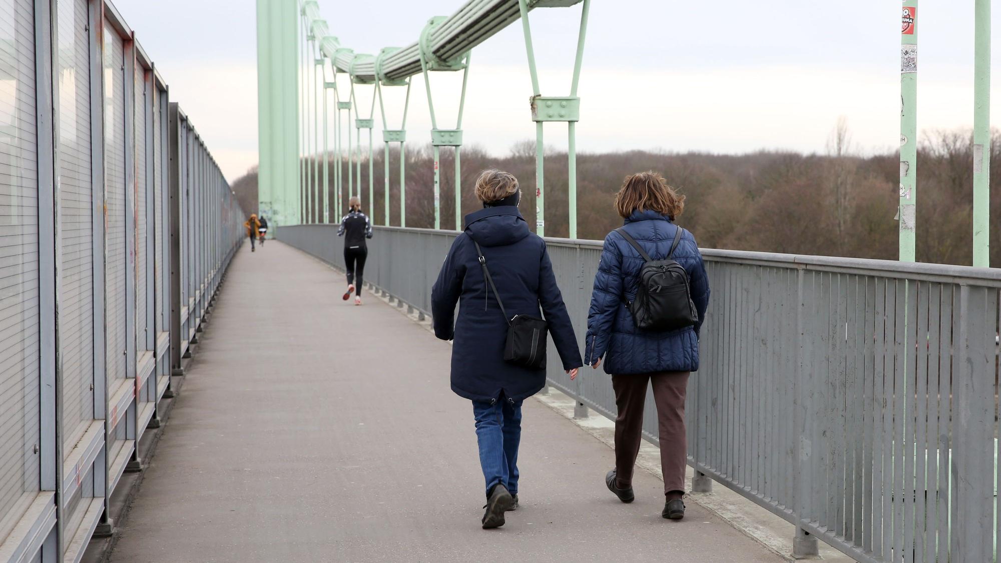 Zwei Frauen laufen über eine Brücke.