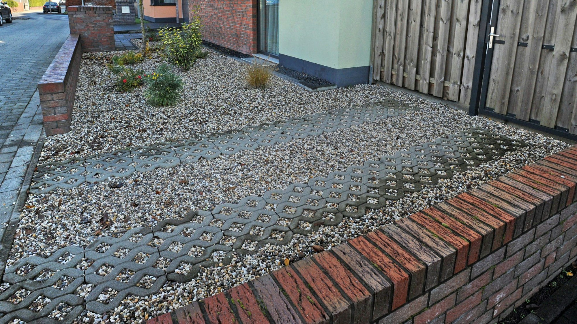 Vorgarten mit Steinbeet und wenigen Pflanzen.