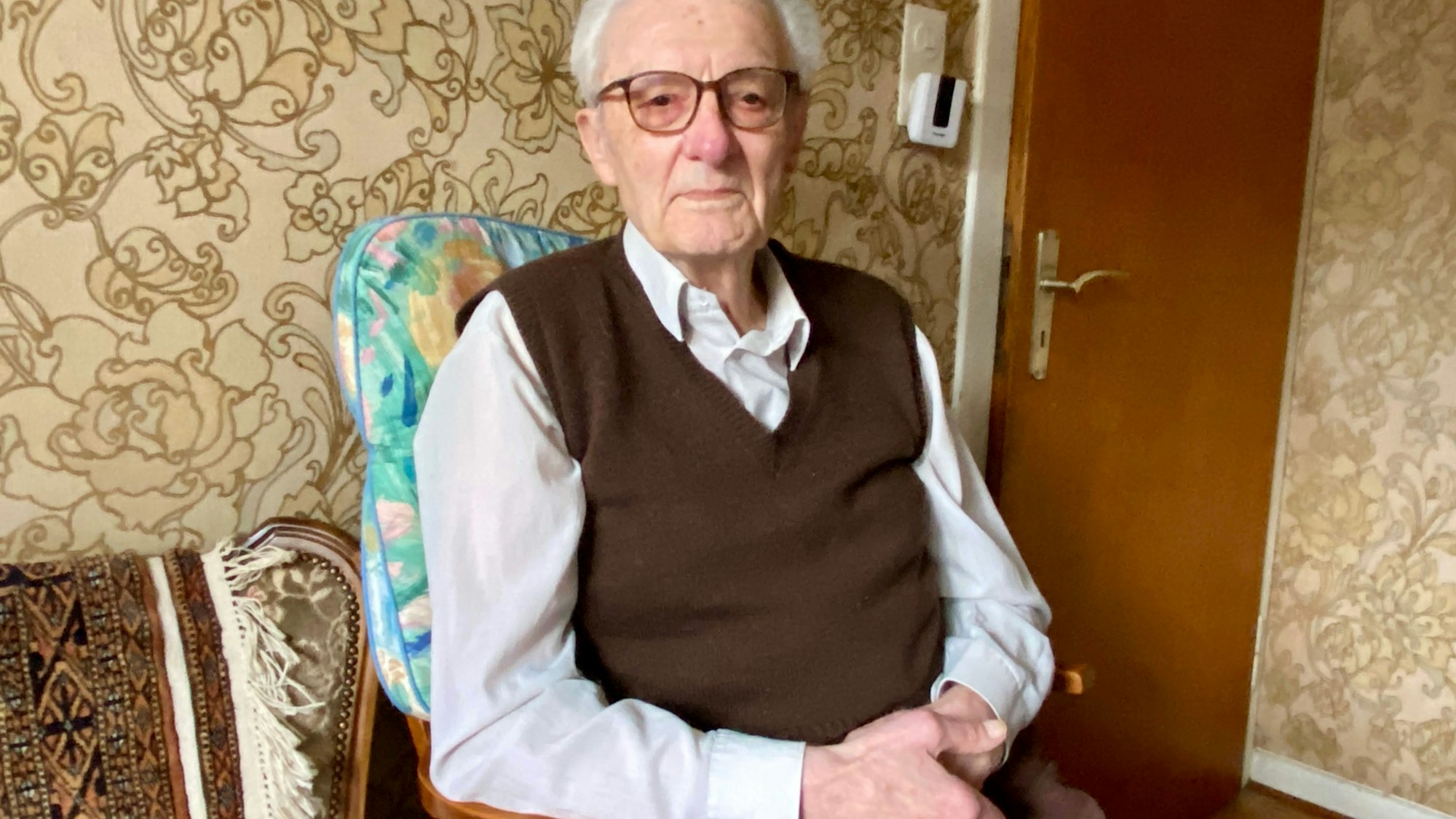 Karl Romberg sitzt auf einem Stuhl.