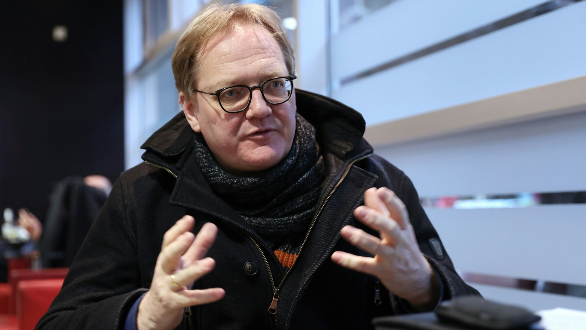 Der Kölner Staatsrechts-Professor Stephan Rixen gestikuliert mit beiden Händen im Gespräch mit seinem Interviewer Joachim Frank.