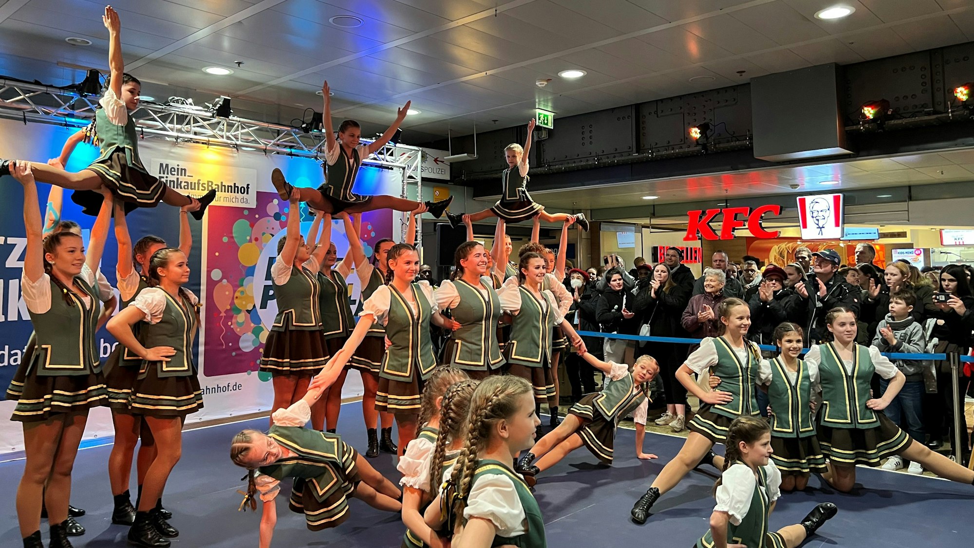 Kindertanzgruppe auf einer Bühne im Kölner Hauptbahnhof in Kostümen.