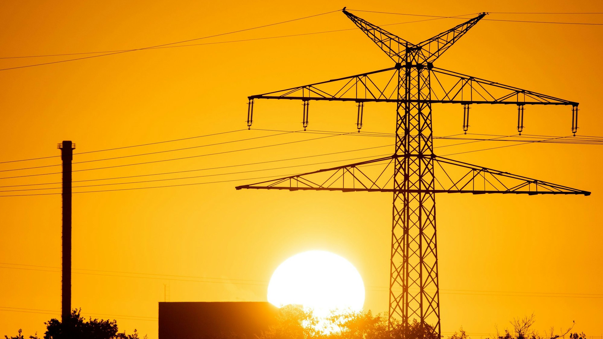Eine Hochspannungsleitung vor der untergehenden Sonne.