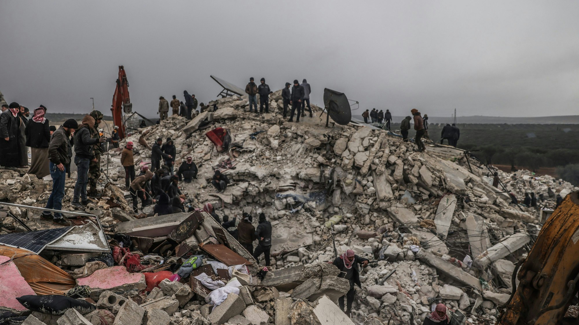 Rettungskräfte und Zivilisten suchen nach Menschen in den Trümmern eines zerstörten Gebäudes.