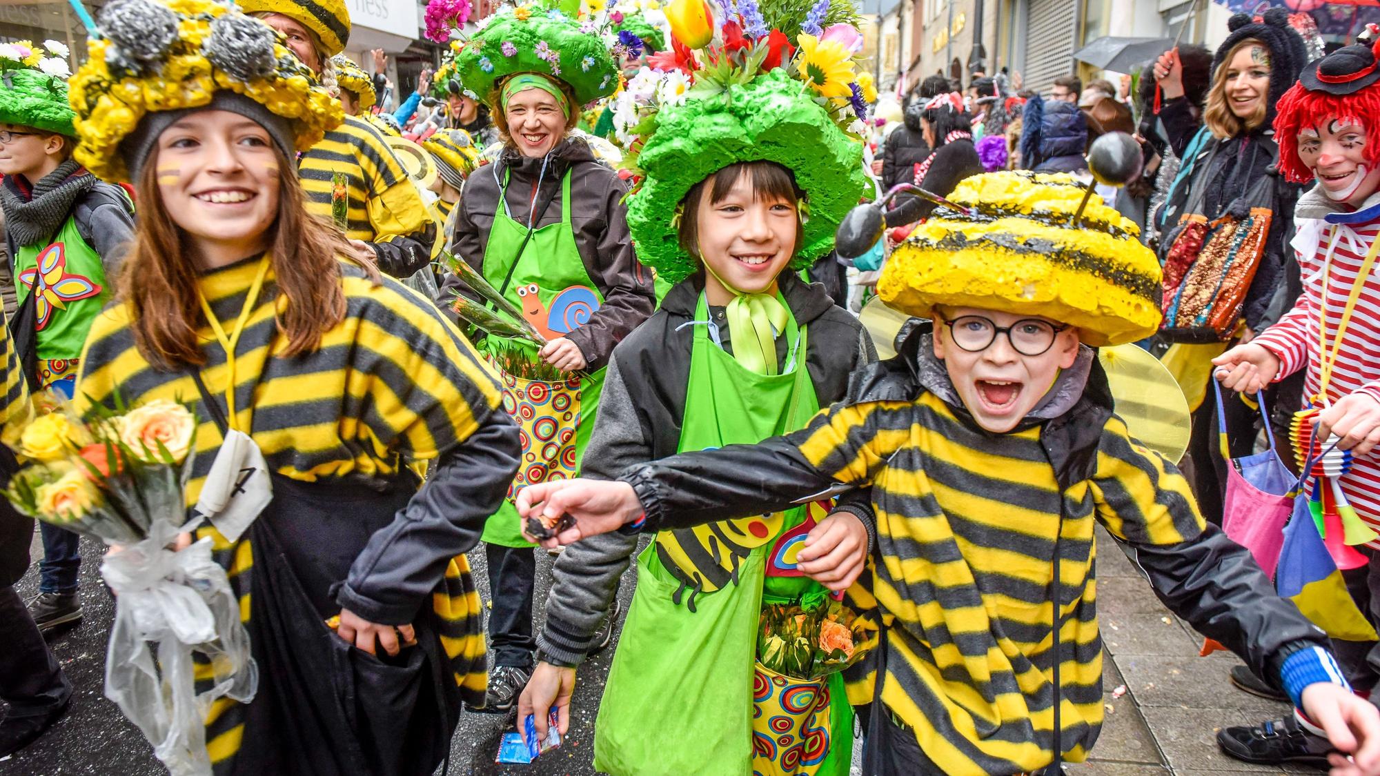 Teilnehmer der Schull- un Veedelszöch laufen über die Severinstraße. Bei diesem Karnevalsumzug nehmen nur Schulen und Vereine aus den Kölner Stadtteilen (Veedeln) teil. Das Bild zeigt als Bienen und Blumen kostümierte Kinder während eines Umzugs 2019.