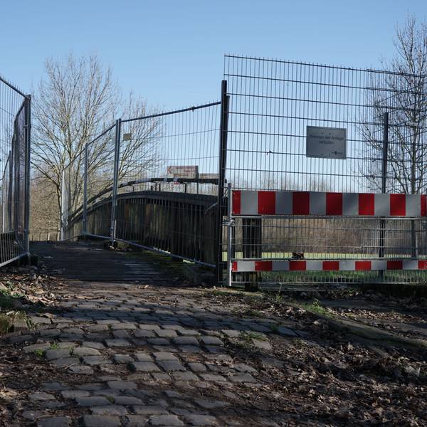 Man sieht eine schmale Brücke über ein Gewässer, welche an den Geländern durch Bauzäune begrenzt wird.
