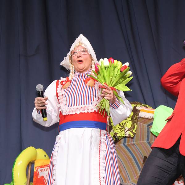 Zwei Frauen stehen auf der Bühne. Eine verkleidet als Frau Antje, mit bunten Tulpen in der Hand, die andere als Heino, der in ein Mikrofon singt.