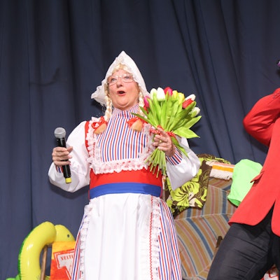 Zwei Frauen stehen auf der Bühne. Eine verkleidet als Frau Antje, mit bunten Tulpen in der Hand, die andere als Heino, der in ein Mikrofon singt.