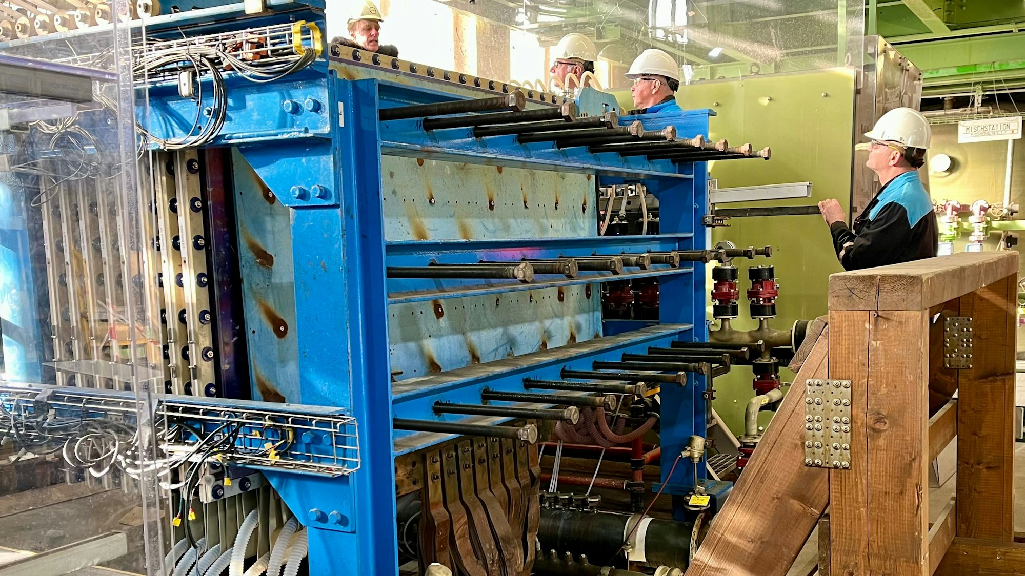 Andreas Bulan, Michael Großholz und Roberto Warte stehen hinter dem Versuchs-Elektrolyseur bei Covestro.