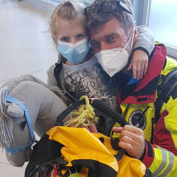 man sihet Vater und Tochter, wie sie in die Kamera gucken, sie tragen Masken. Ingo hat sich neben Mia gekniet, diese hat den Arm um seinen Hals.
