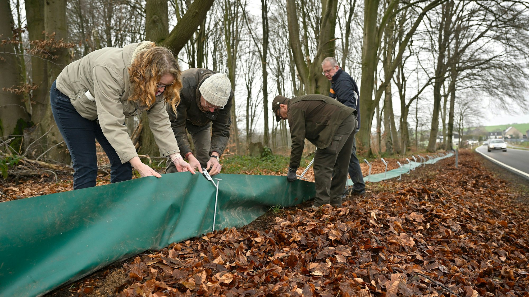Personen spannen Planen wie Zäune ein Stück vor die Straße.