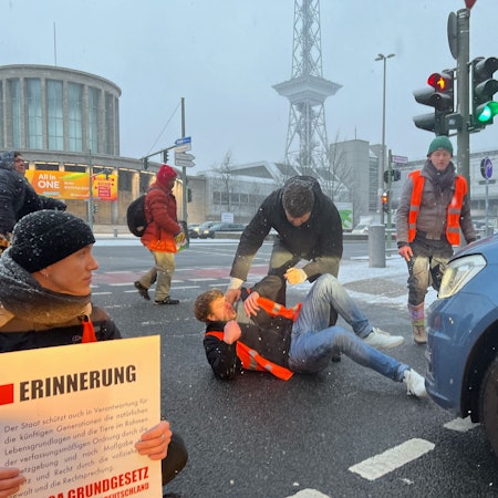 An der Autobahnausfahrt A100 und A115 haben sich gegen am Morgen mehrere Aktivisten der letzten Generation festgeklebt. Es kam zu mehreren Auseinandersetzungen mit Autofahrern. Dem hier liegenden Demonstranten fuhr ein Auto über den Fuß, wie in einem Video zu sehen ist.