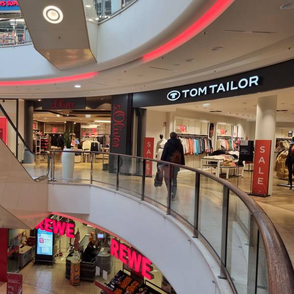 Eine Frau geht am Geschäft von Tom Tailor vorbei. Daneben befindet sich das Geschäft von S.Oliver.