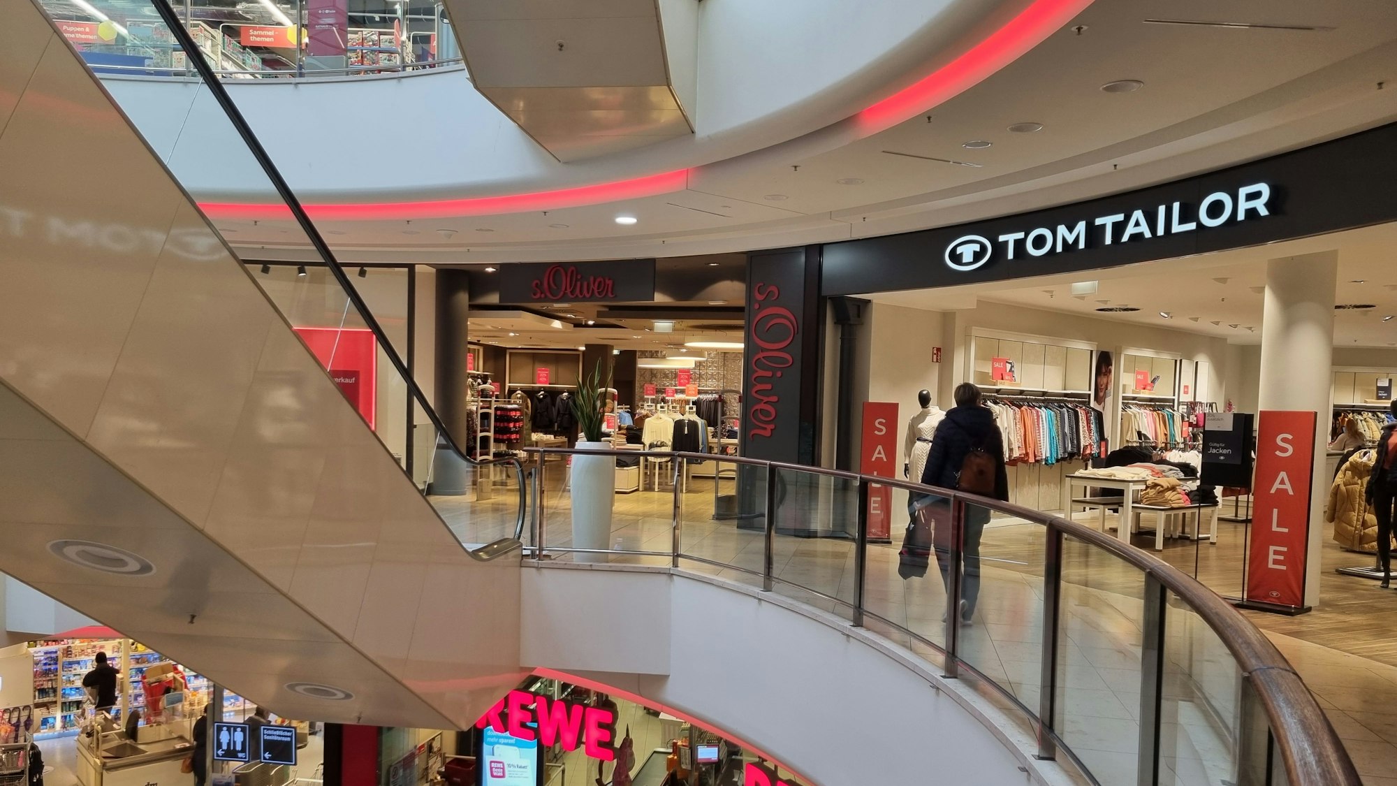 Eine Frau geht am Geschäft von Tom Tailor vorbei. Daneben befindet sich das Geschäft von S.Oliver.