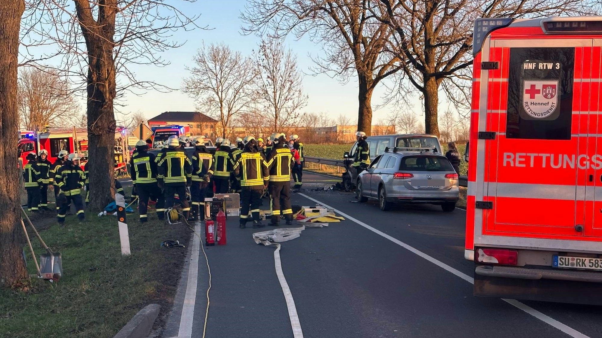 Eine Traube Feuerwehrleute stehen an einem Auto. Ein Rettungswagen steht daneben, zwei weitere Autos ebenfalls.