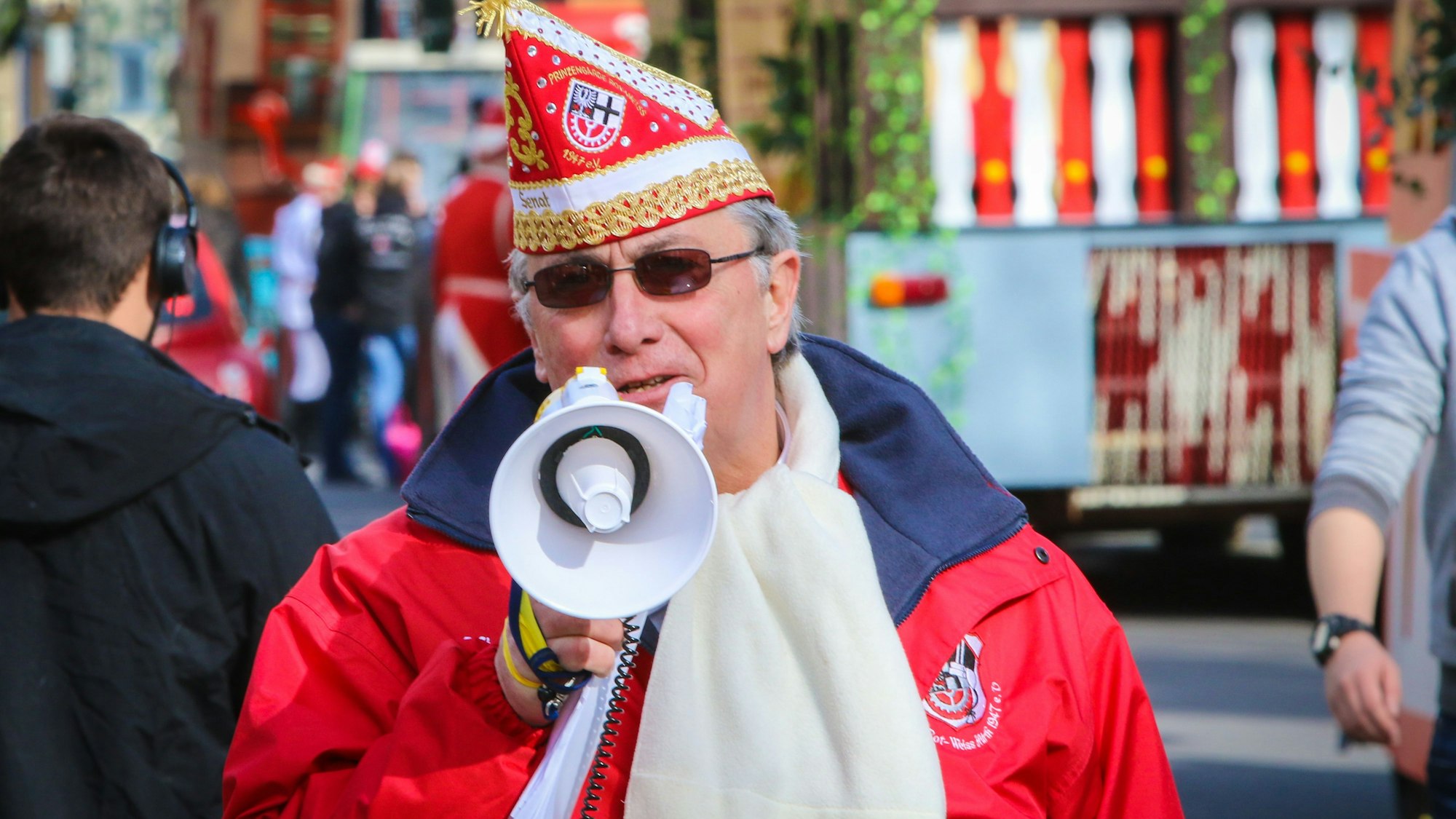 Michael Over mit Narrenkappe beim Zug. Durchs Mikrofon gibt er Anweisungen.