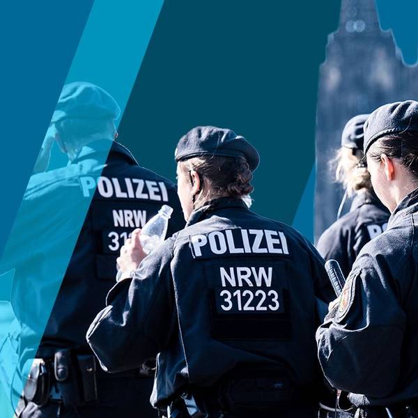 Polizisten einer Hundertschaft gehen hintereinander her.