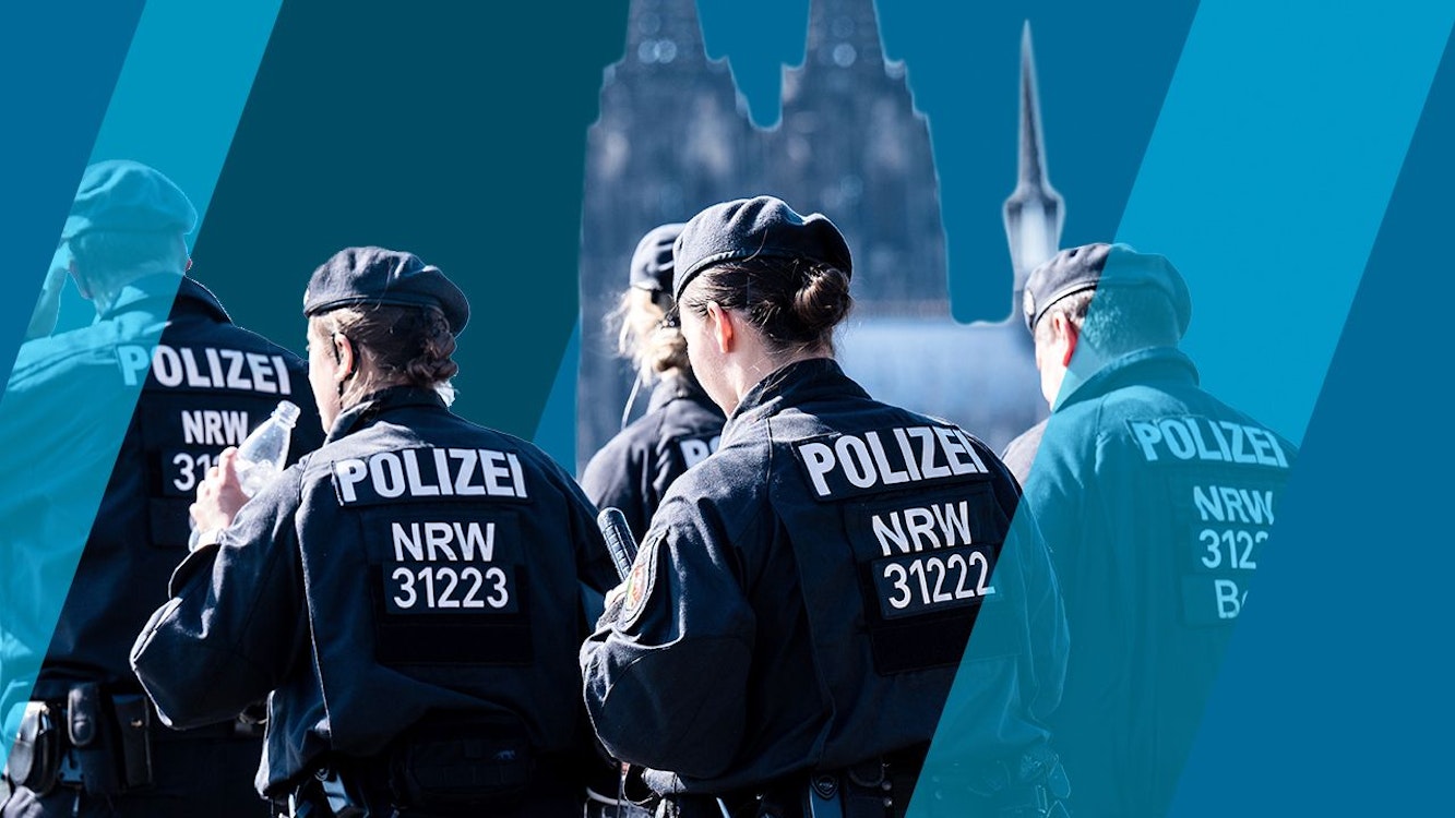 Polizisten einer Hundertschaft gehen hintereinander her.