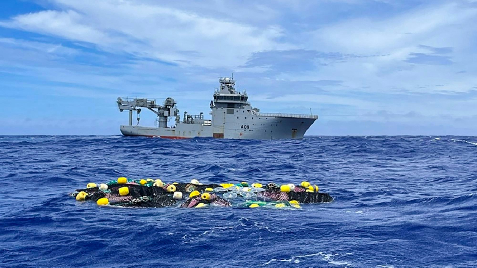 Auf diesem Foto der neuseeländischen Polizei schwimmt eine Ladung Kokain auf der Oberfläche des Pazifischen Ozeans, dahinter das Schiff HMNZS Manawanui der Royal New Zealand Navy.