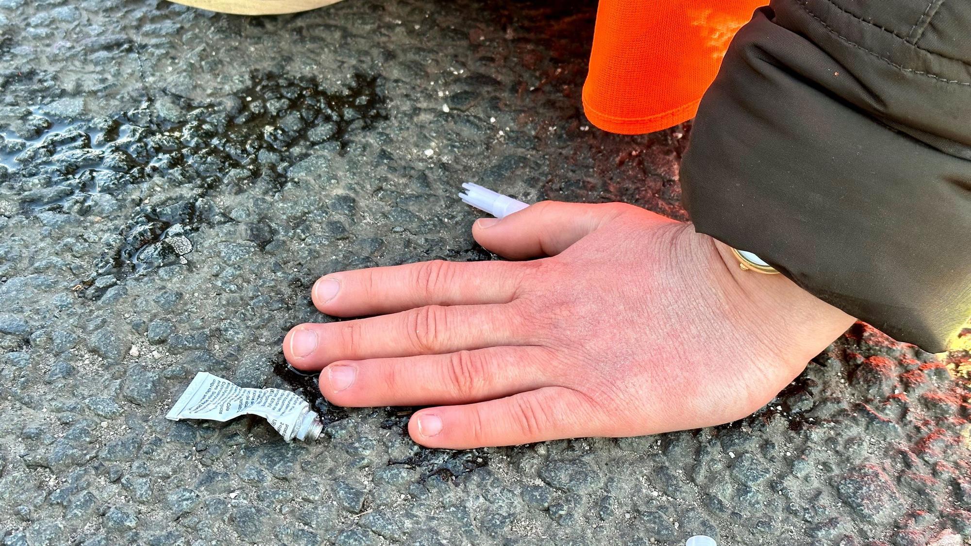 Eine Klimaaktivistin hat sich mit einer Hand auf einer Hauptverkehrsstraße festgeklebt.