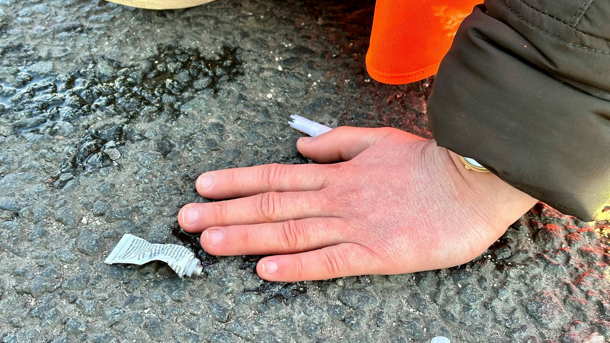 Eine Klimaaktivistin hat sich mit einer Hand auf einer Hauptverkehrsstraße festgeklebt.