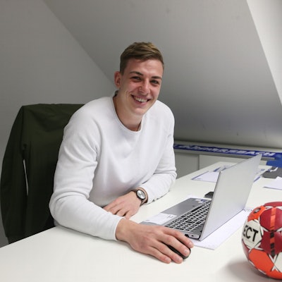 Blick auf einen jungen Mann am Schreibtisch.