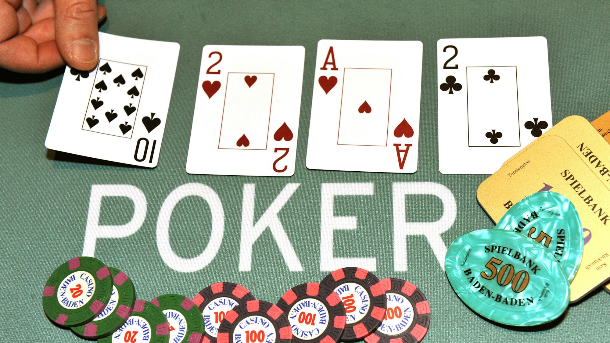 Ein Dealer legt bei einem Pokerspiel die Pokerkarten auf den Tisch.