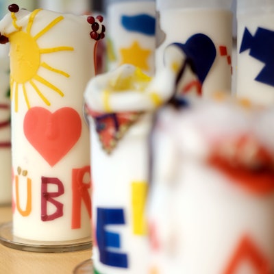 Bunte Kerzen stehen in einer langen Reihe auf einem Regal.