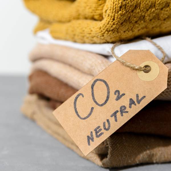 Mehrere Wollpullover liegen gefaltet auf einem Stapel. Daran hängt ein Schild mit der Aufschrift: "CO₂-neutral".