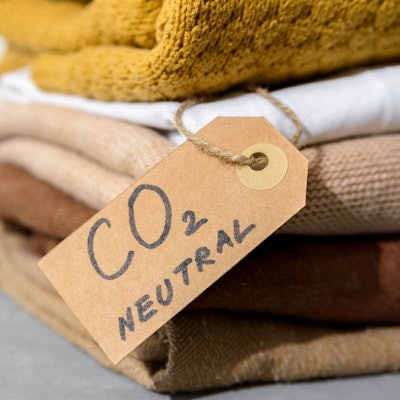 Mehrere Wollpullover liegen gefaltet auf einem Stapel. Daran hängt ein Schild mit der Aufschrift: "CO₂-neutral".