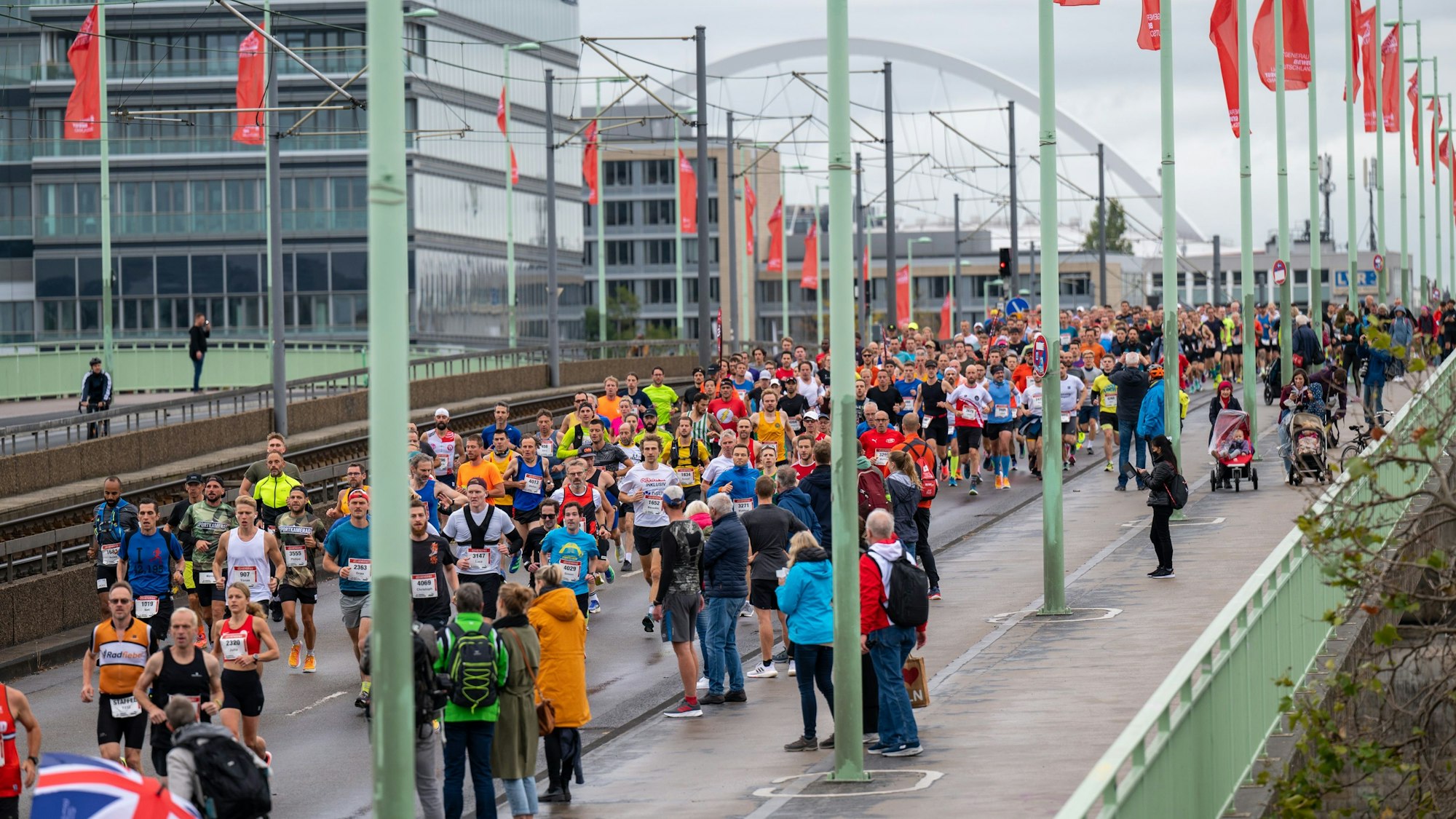 Etliche bunt gekleidete Läuferinnen und Läufer überqueren die Deutzer Brücke.