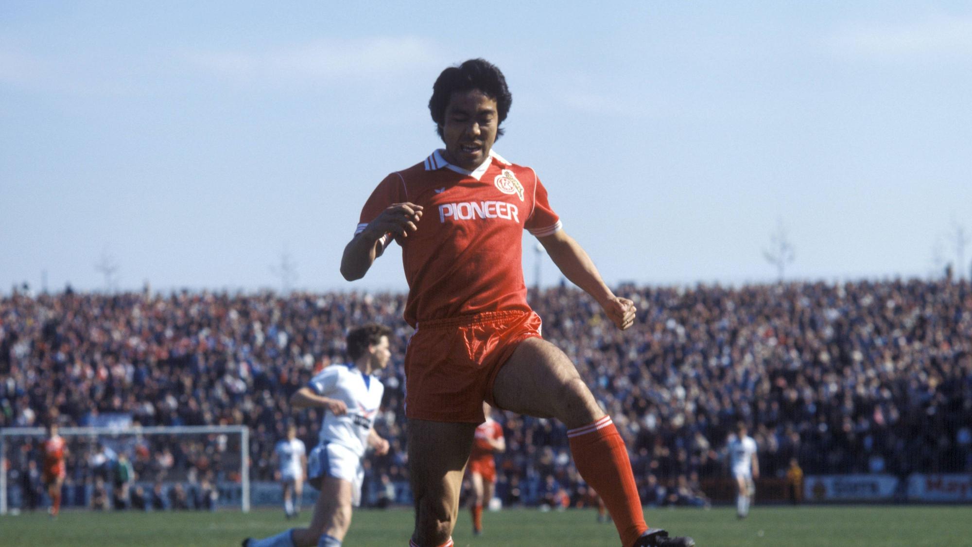 Der Japaner Yasuhiko Okudera vom 1. FC Köln springt über den am Boden liegenden Schalker Torwart Norbert Nigbur.