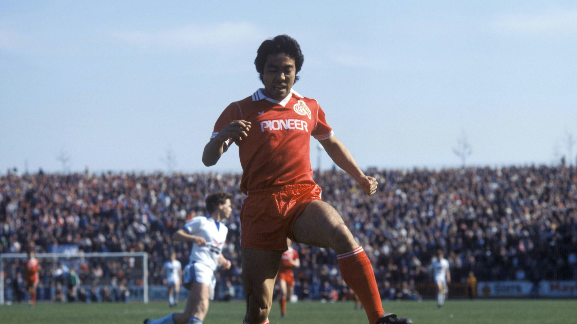 Der Japaner Yasuhiko Okudera vom 1. FC Köln springt über den am Boden liegenden Schalker Torwart Norbert Nigbur.