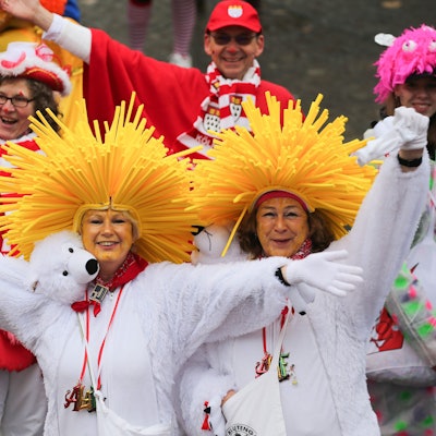 Es sind verkleidete Menschen zu sehen, die in die Kamera winken.