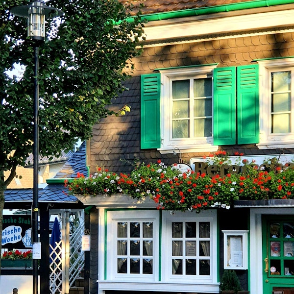 Foto eines Gasthauses in Burscheid mit Blumen und Biergartenstühlen.