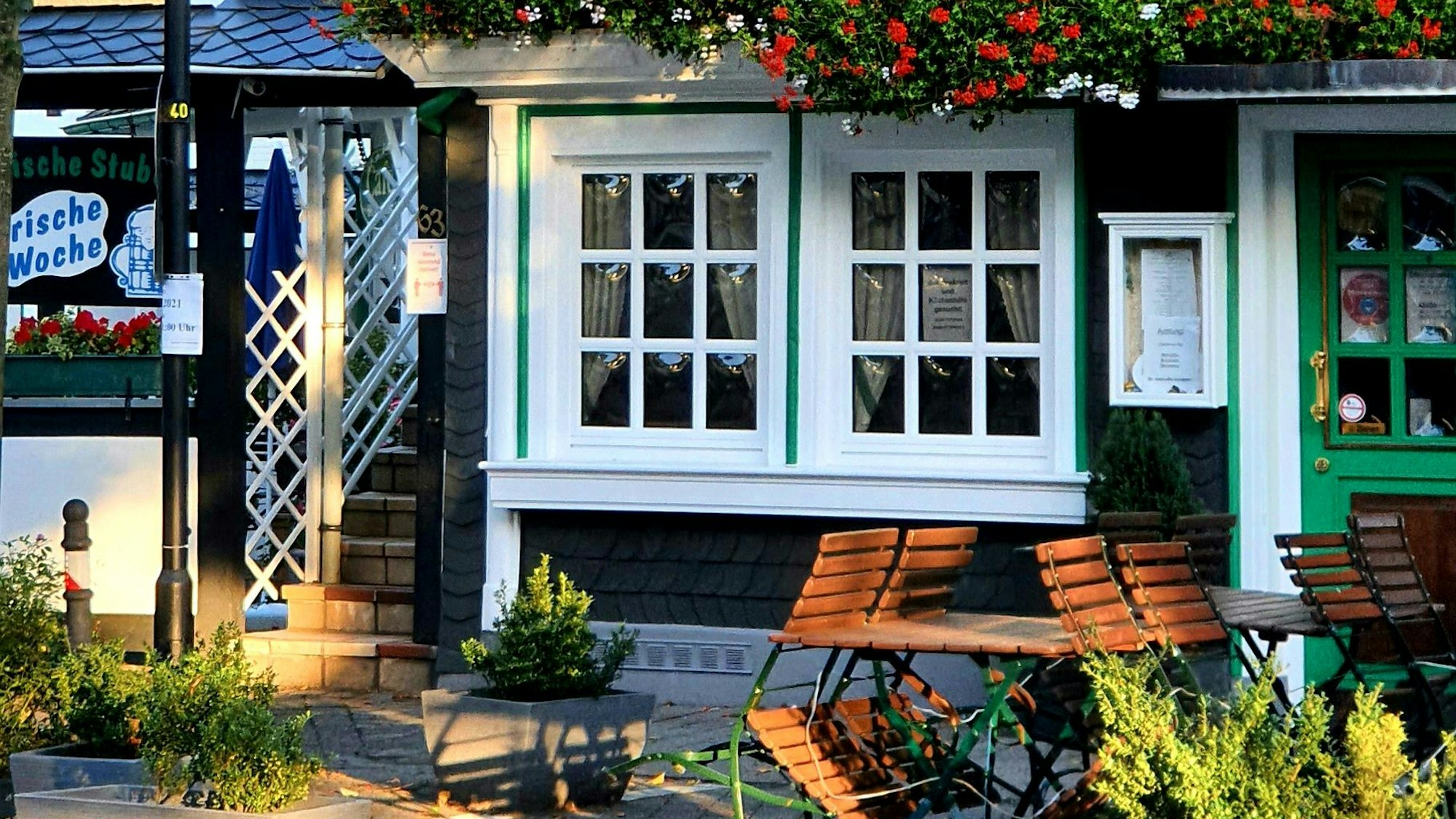 Foto eines Gasthauses in Burscheid mit Blumen und Biergartenstühlen.