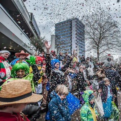 Eine verkleidete Frau wirft auf dem Wiesdorfer Karnevalszug Konfetti.