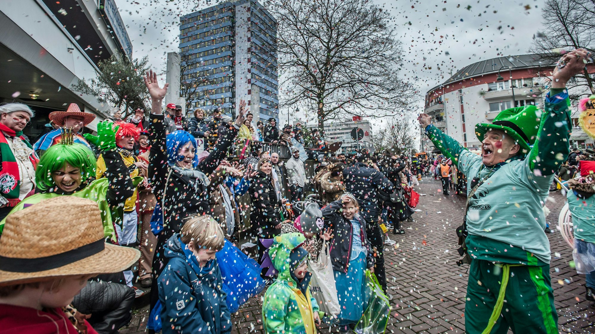 Eine verkleidete Frau wirft auf dem Wiesdorfer Karnevalszug Konfetti.