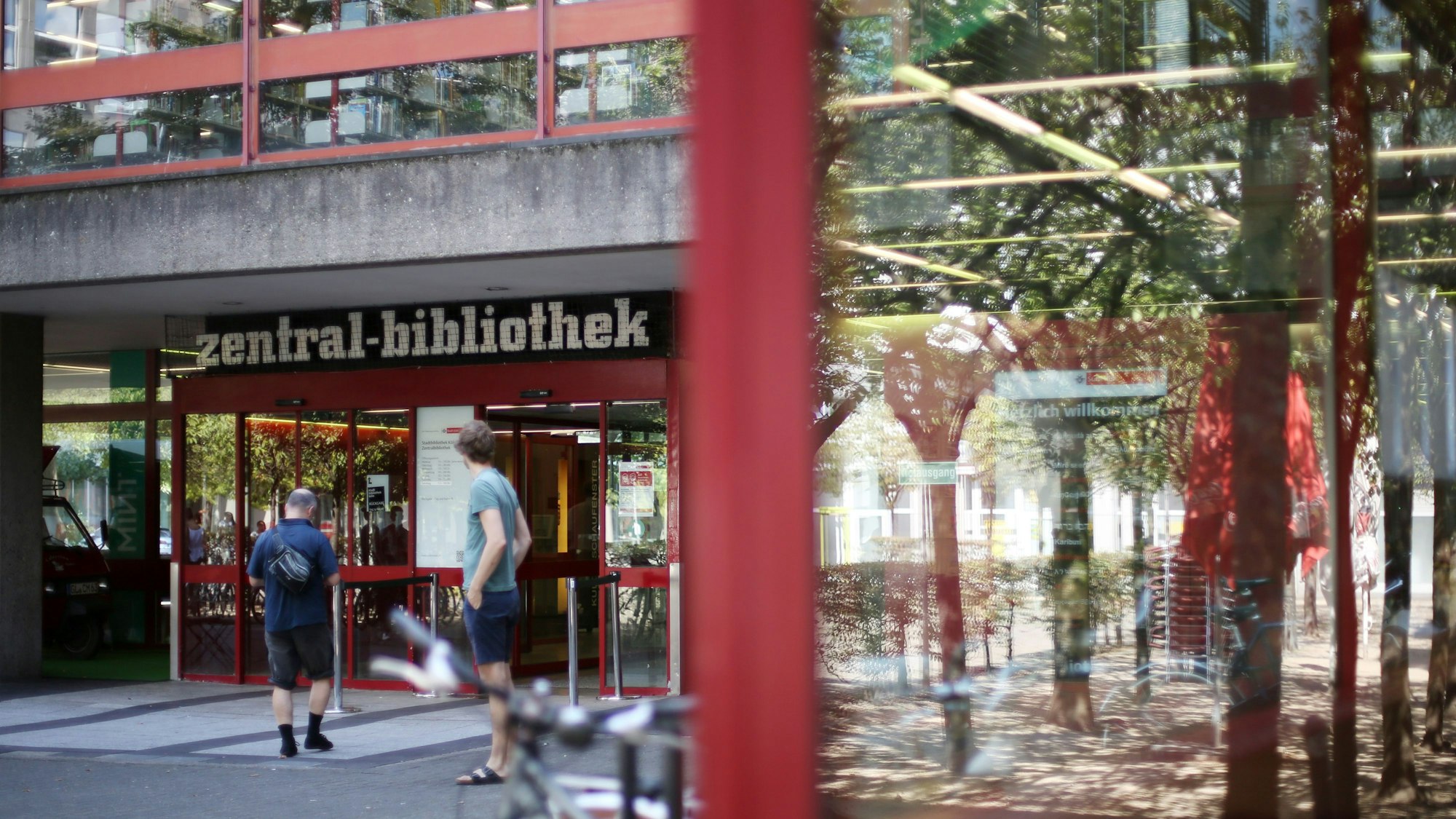 Das Bild zeigt die Zentralbibliothek von außen, davor stehen zwei Männer.