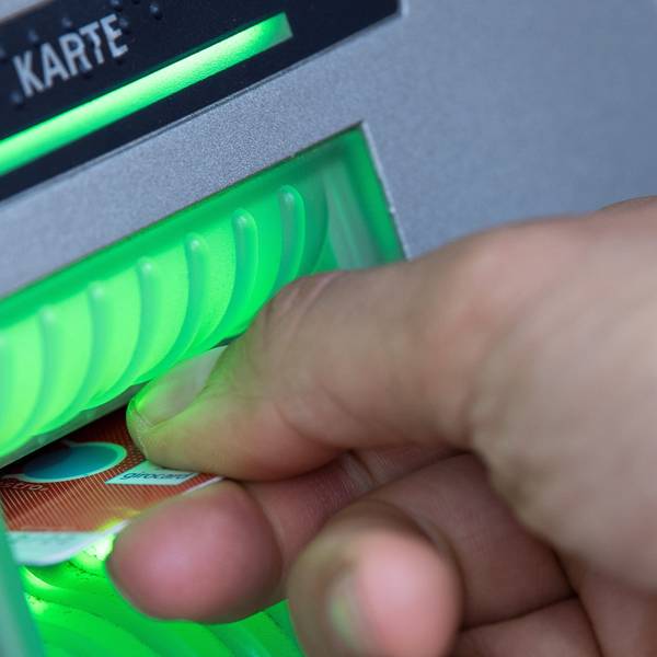 Eine Bankkundin steckt ihre Girokarte in einen Geldautomaten.