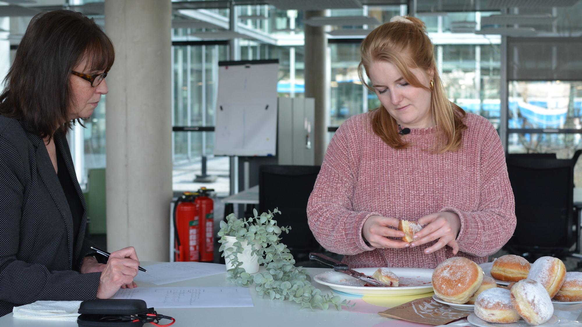 Zwei Frauen am Tisch, darauf liegen Berliner.