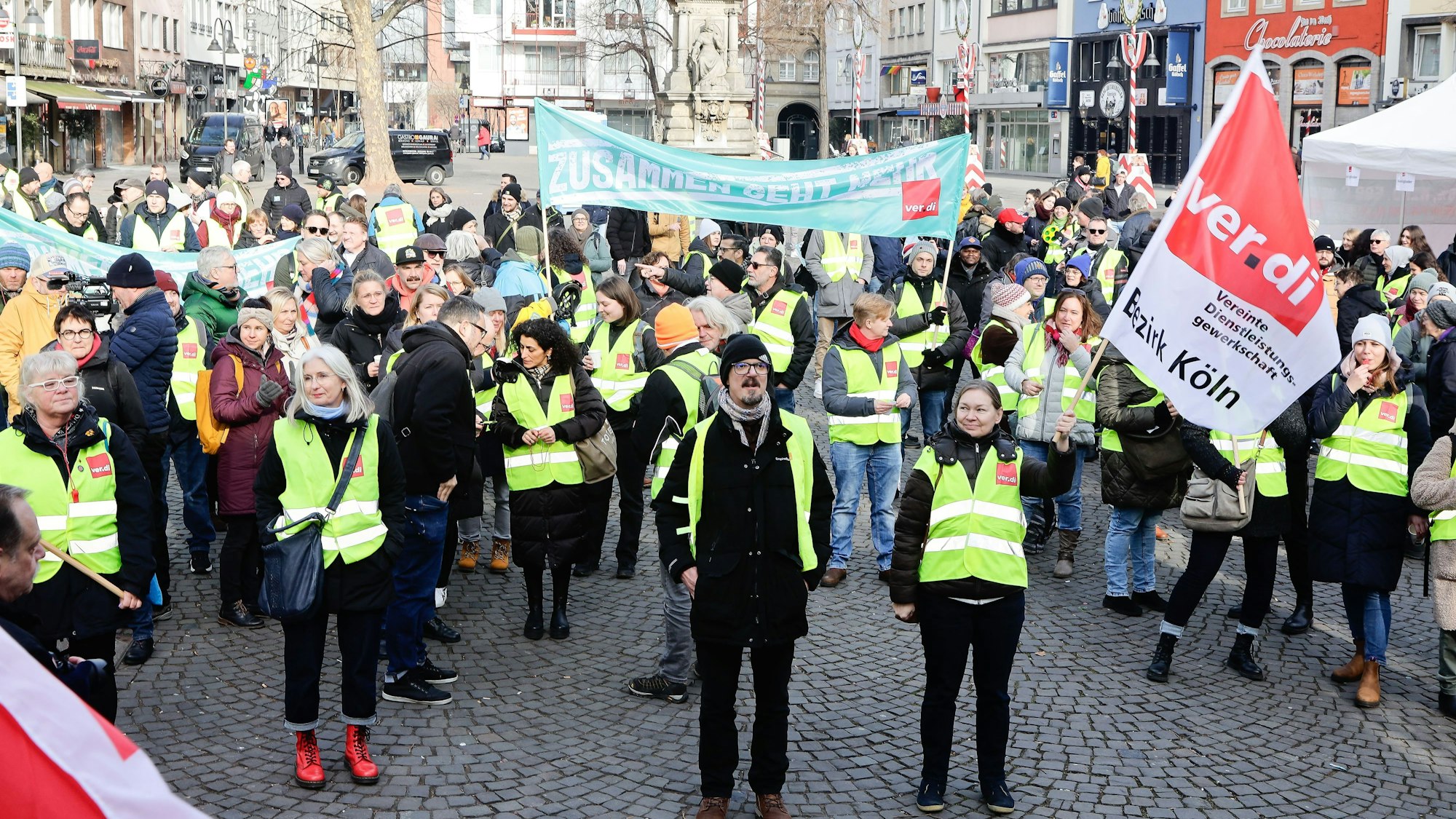 Mit gelben Warnwesten und mit Transparenten stehen die Beschäftigten auf dem Alter Markt.
