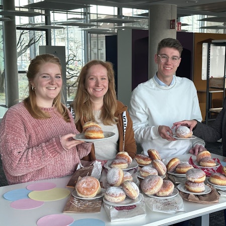 Vier Menschen stehen vor einem Tisch, auf dem viele Berliner liegen.